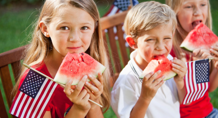 kids eating watermelon and holding American flags
